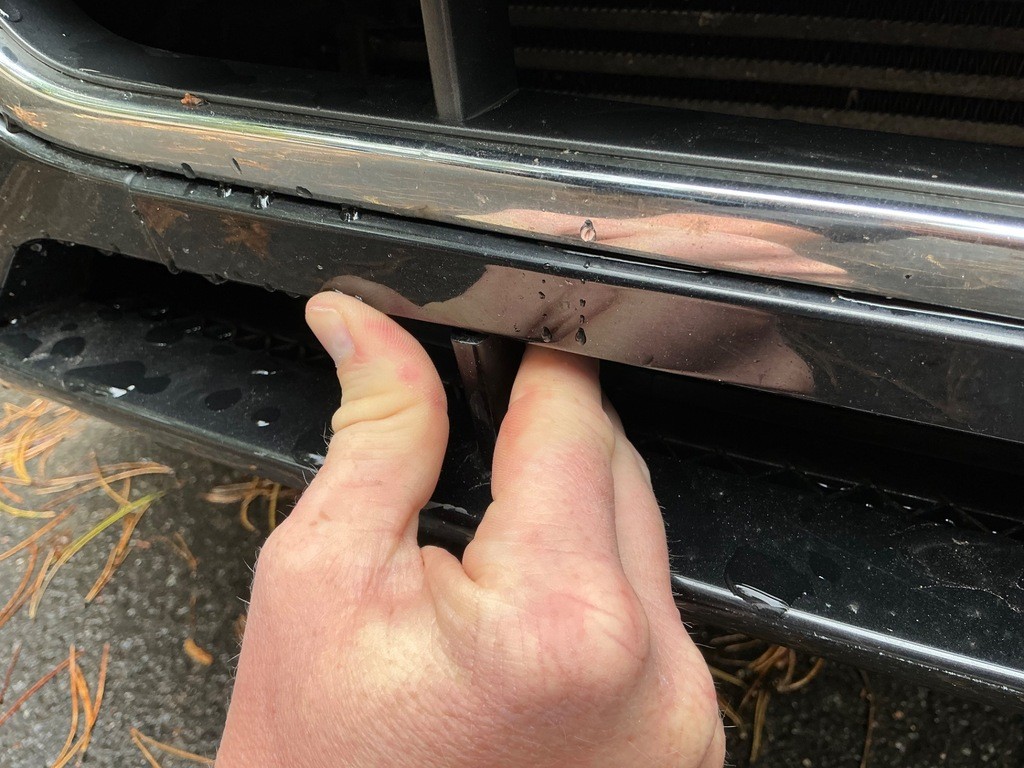 Nahaufnahme Frontgrill mit Lackschäden und Kratzern, Hand zeigt Schadenstelle