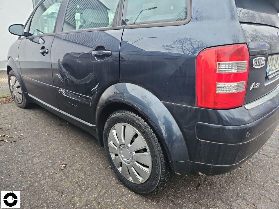 Heckansicht schräg links, deutliche Delle und Kratzer an hinterer linker Tür und Seitenwand