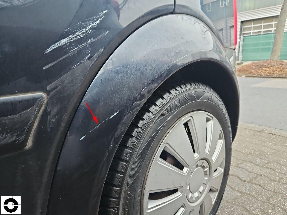 Hinterer linker Kotflügel mit Kratzern und Schrammen, roter Pfeil markiert Schaden