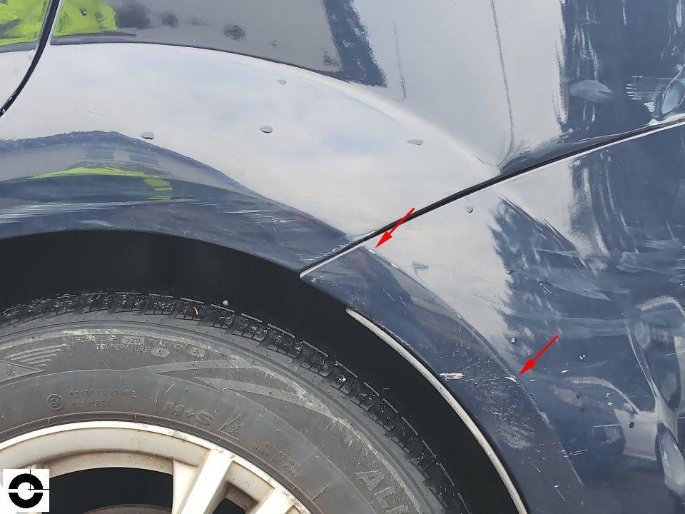 Detailaufnahme hinterer Radlauf links mit Spaltmaßabweichung und Kratzer, rote Pfeile markieren Schäden