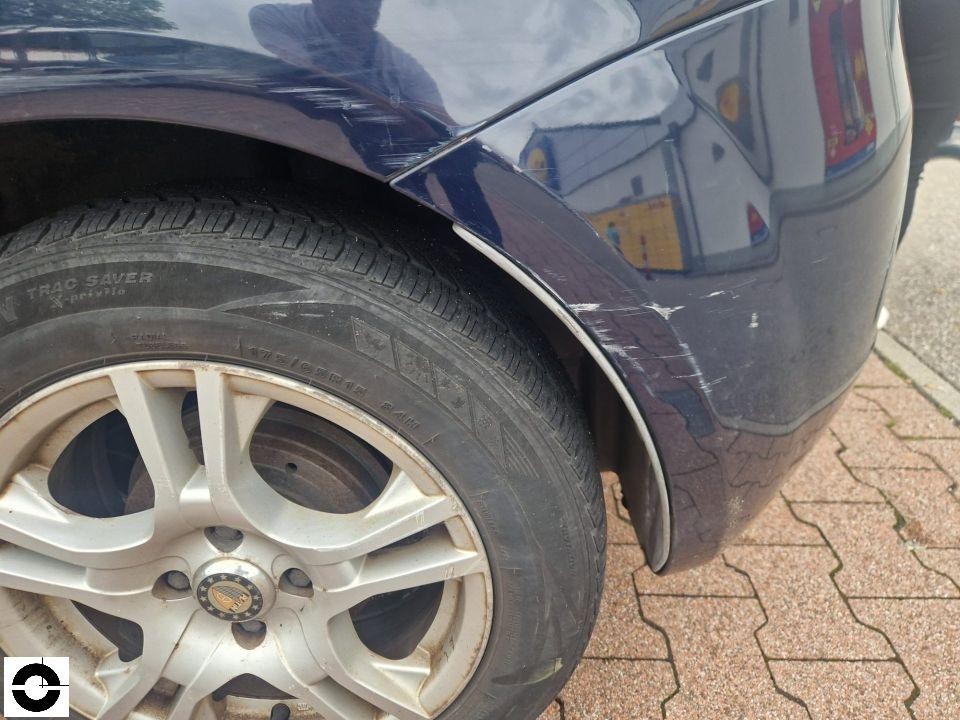 Nahaufnahme hinterer linker Kotflügel mit Kratzern und Lackschäden an Radlaufkante